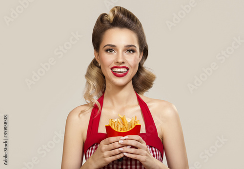Smiling pin-up girl holding a french fries in her hands