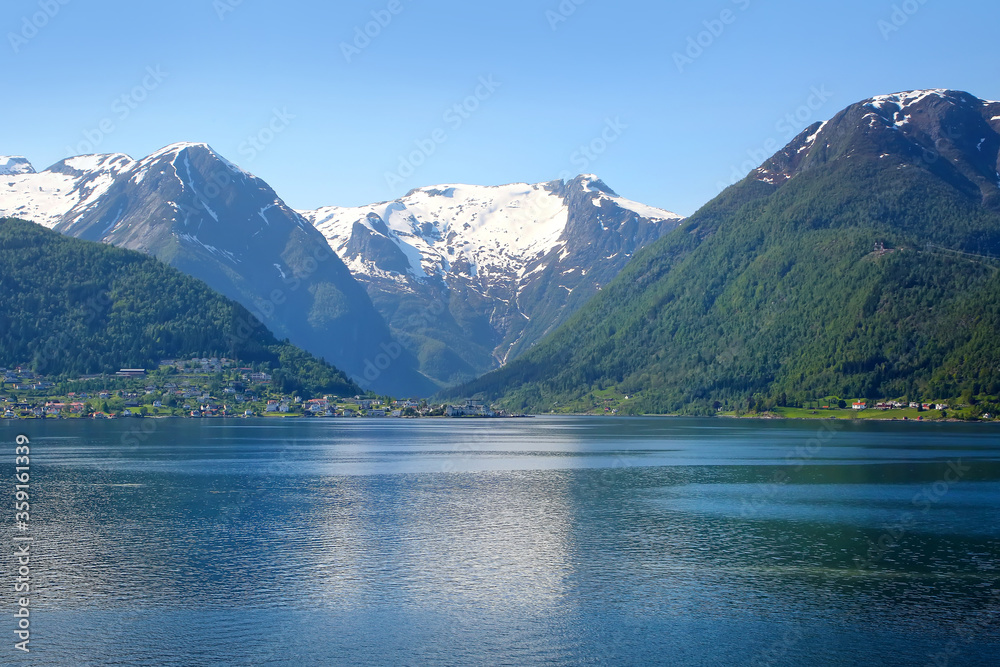 Beautiful calm Norwegian fjord landscape. Snow on the mountains and reflections in the water of the Sognefjord or Sognefjorden, Vestland county in Western Norway.
