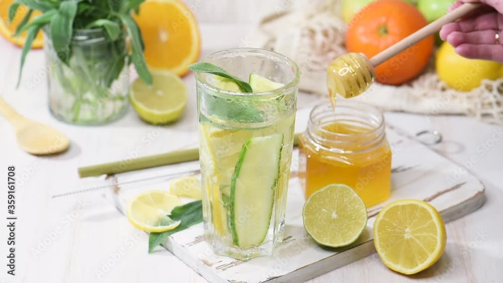 Citrus lemonade in a glass with drops and ice cubes. Fruit water with honey, summer beverage on a wooden table Citrus lemonade in a glass with drops and ice cubes. Fruit water with honey, summer beverage on a wooden table