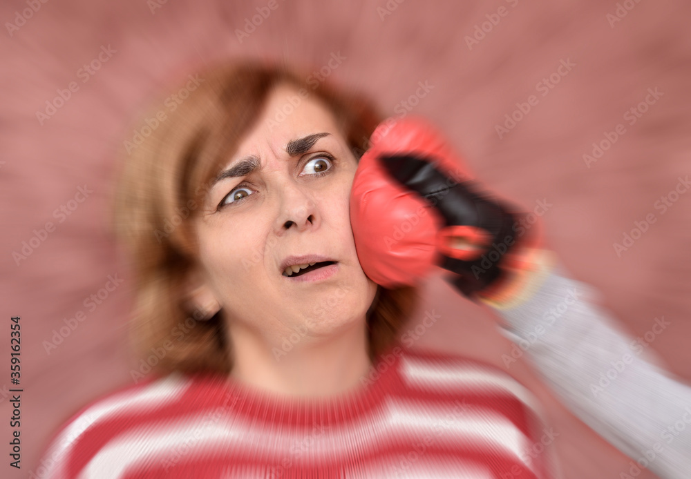 Woman getting hit in her face with red boxing glove. Radial blur effect applied around her face. Woman getting hit in her face with red boxing glove. Radial blur effect applied around her face.