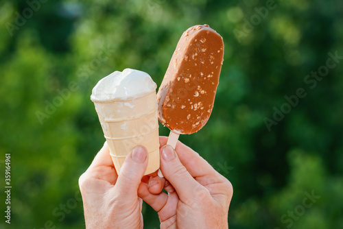 Hand holding ice cream on blurred natural background photo