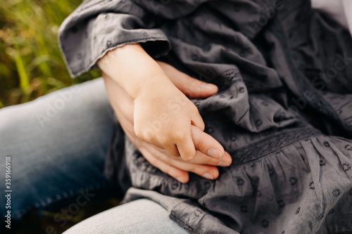 Little girl holding father's hand, close-up, outdoors in a park.