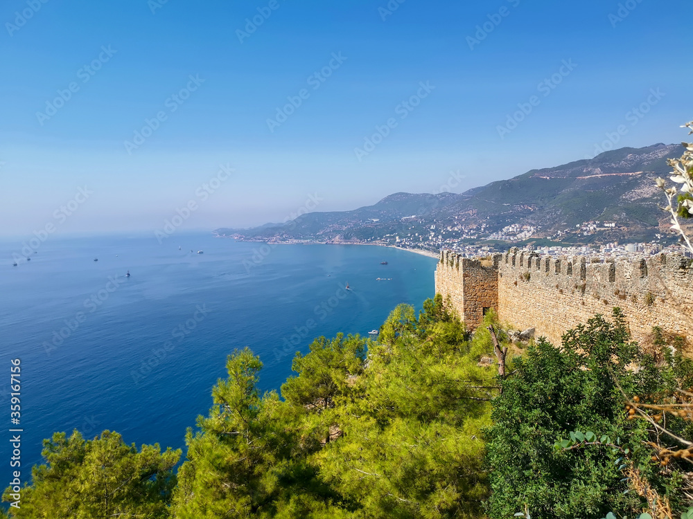 View of the fortress wall and the sea coast of the city of Alanya on a sunny day. View from above.
