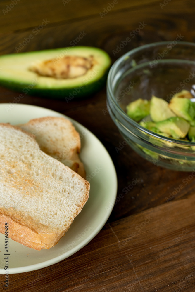 Fried bread for toasts and avocado for breakfast in the morning on brown woodwn table. Close-up Fried bread for toasts and avocado for breakfast in the morning on brown woodwn table. Close-up