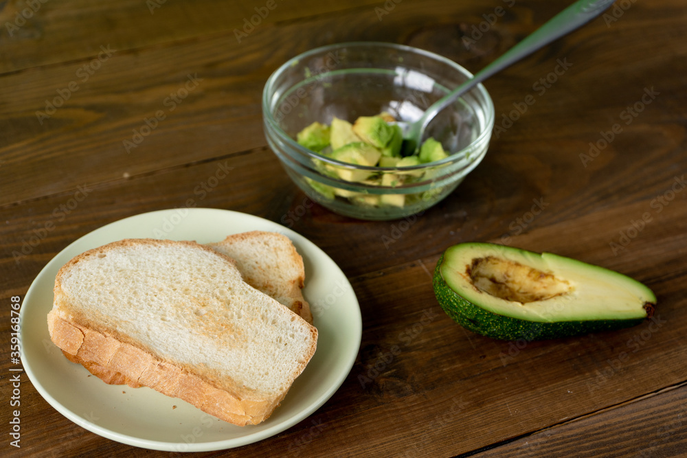 Fried bread for toasts, avocado and honey for breakfast in the morning on brown woodwn table on green background. Fried bread for toasts, avocado and honey for breakfast in the morning on brown woodwn table on green background.
