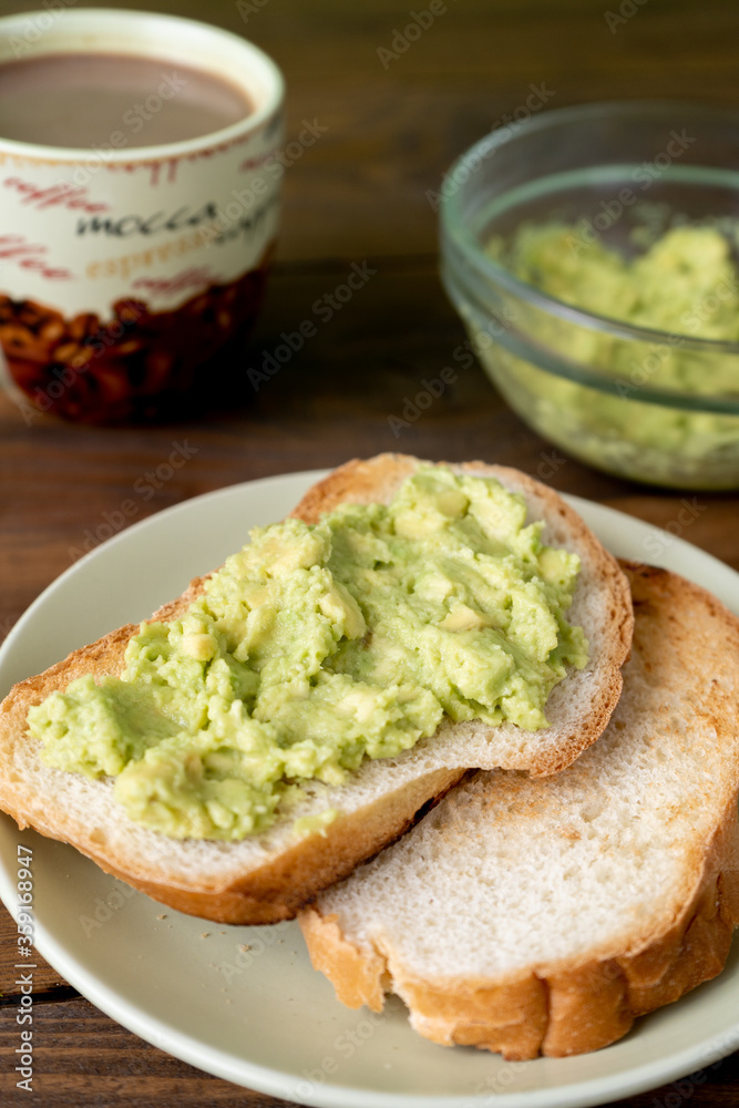 Fresh tasty toasts with avocado and a cup of coffee for breakfast on brown wooden table. Vertical. Fresh tasty toasts with avocado and a cup of coffee for breakfast on brown wooden table. Vertical.