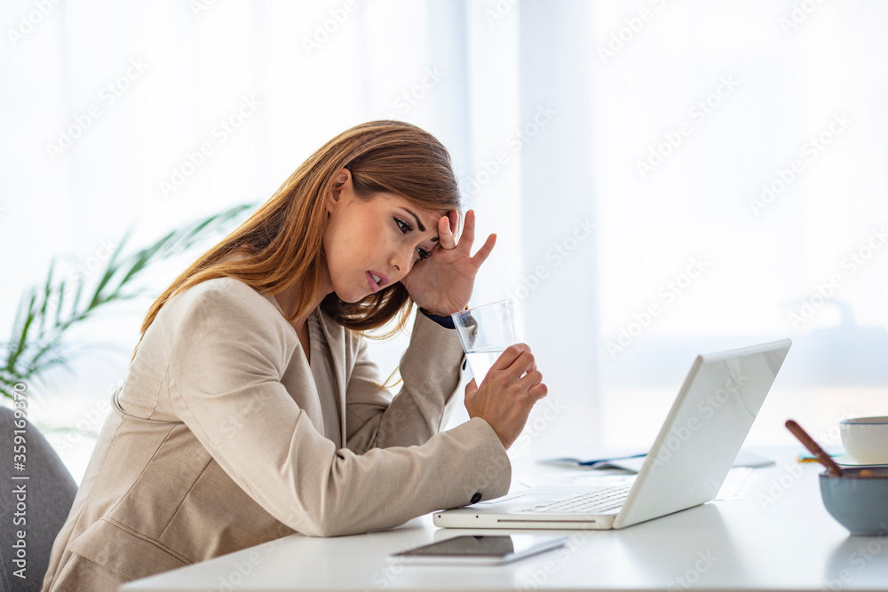 Shot of a young businesswoman looking stressed out while working in an office. When the road to success leads to stress. Woman suffering from stress while using a computer at her work desk Shot of a young businesswoman looking stressed out while working in an office. When the road to success leads to stress. Woman suffering from stress while using a computer at her work desk