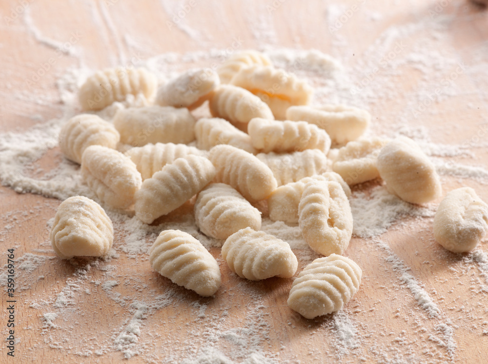 Gnocchi sobre tabla de madera con harina, vista cenital. Gnocchi on wooden board with flour, overhead view. Gnocchi sobre tabla de madera con harina, vista cenital. Gnocchi on wooden board with flour, overhead view.
