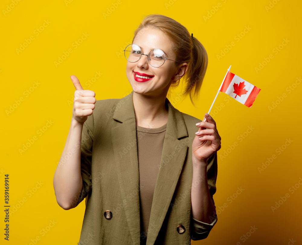 Style blonde woman in jacket with Canadian flag on yellow background