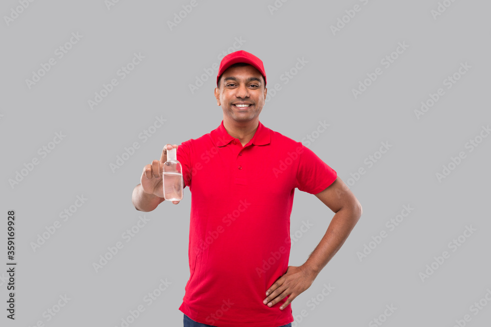 Naklejka premium Indian Delivery Man Holding Hands Sanitizer. Hands Antiseptic. Man in Red T shirt. Health, Isolation Concept