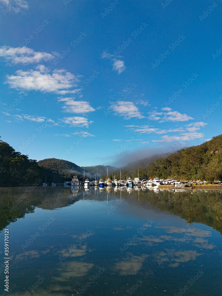 Beautiful morning view of Cowan creek with reflections of blue sky, boats, mountains and trees, Bobbin Head, Ku-ring-gai Chase National Park, New South Wales, Australia Beautiful morning view of Cowan creek with reflections of blue sky, boats, mountains and trees, Bobbin Head, Ku-ring-gai Chase National Park, New South Wales, Australia