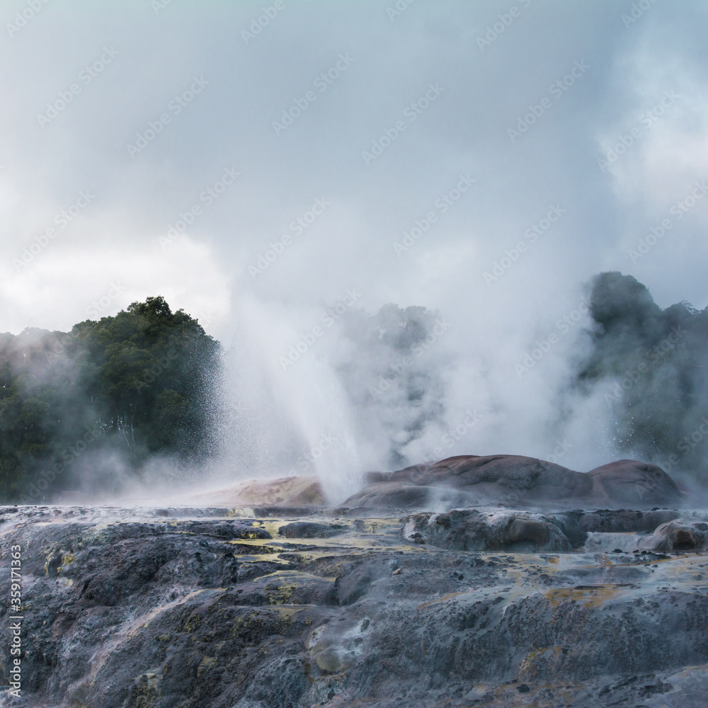 Active geysers erupting above rocks