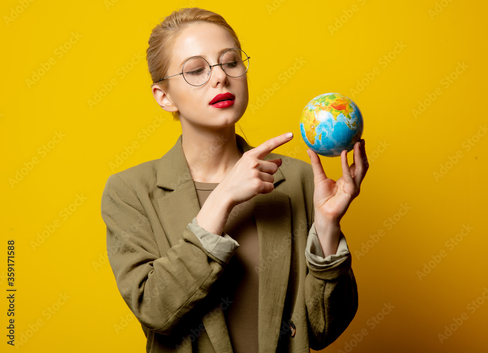 Fototapeta premium Style blonde woman in jacket hold Globe on yellow background