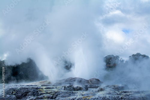 Two geysers erupting above rocks