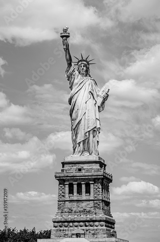 USA: The outdoor Statue of Liberty on a background of blue sky with white clouds on Liberty Island in New York, USA in black and white