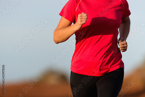 Athlete woman running in red t-shirt and on blue sky background 