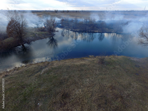 The smoke from the burning of dry grass (drone image).Local residents set fire to the grass specifically. Small animals are bending. Local features and habits. Near Kiev,Ukraine