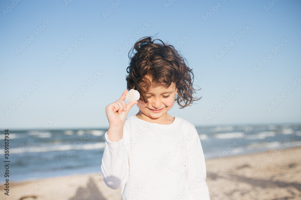 Little cute girl searching seashells on the sea beach Little cute girl searching seashells on the sea beach