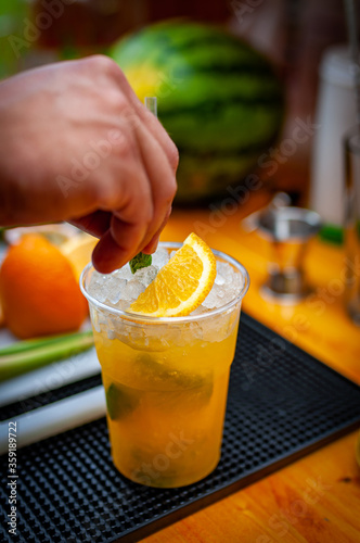 Cocktail preparation with orange, mint, maracuja and ice.