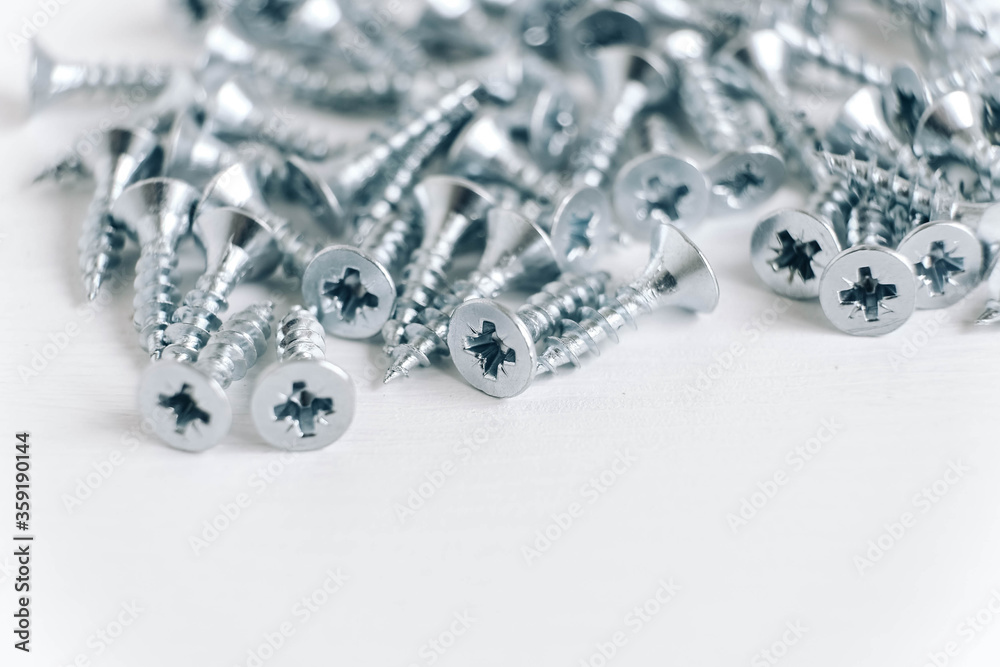 Metal tapping screws for wood on white wooden background. Construction equipment concept. Top view. Copy, empty space for text Metal tapping screws for wood on white wooden background. Construction equipment concept. Top view. Copy, empty space for text