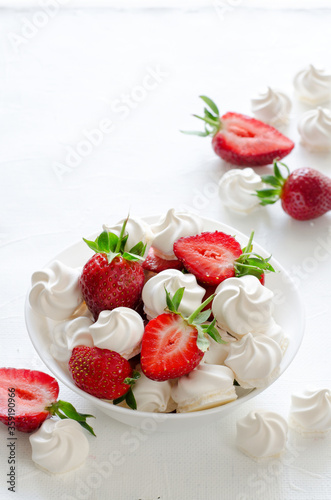 Fresh strawberries and meringues on white background