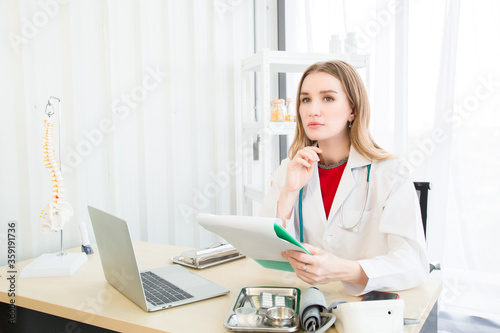 Female beautiful wearing a doctor uniform holding a green paper chart and talking case of treatment.