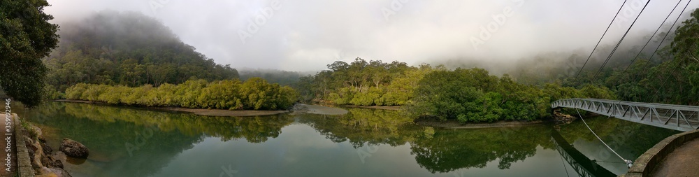 Beautiful morning panoramic view of Cockle creek with reflections of foggy sky, mountains and trees, Bobbin Head, Ku-ring-gai Chase National Park, New South Wales, Australia

