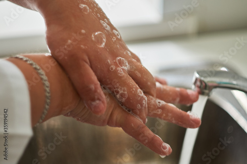 Close up of a medical worker in protective clothing washing her hands.