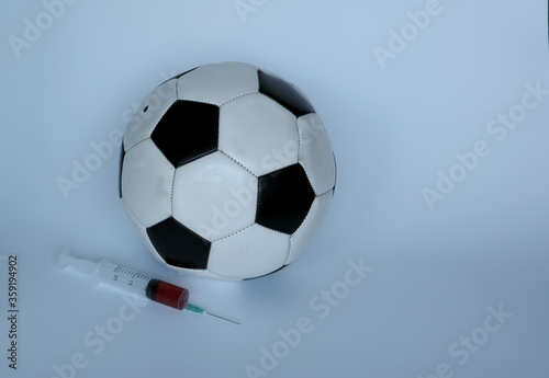 Football  soccer ball near the syringe  on a blue background. The concept of doping in sports. Pharmaceuticals  championship.