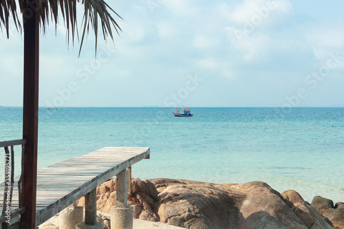 Fishing wooden boat in the ocean. The view from private beach on tropical island. Sailing lifestyle. Koh Munnork island in Thailand.  photo