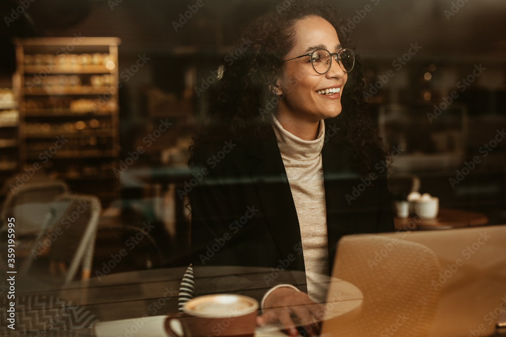 Businesswoman looking outside cafe window and smiling
