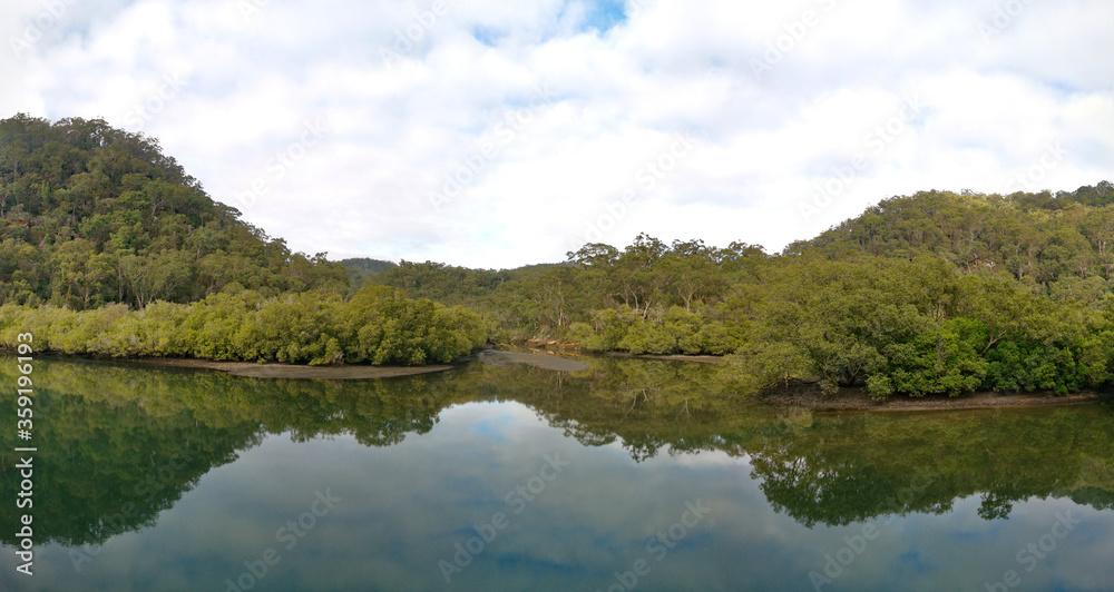 Beautiful morning panoramic view of Cockle creek with reflections of foggy sky, mountains and trees, Bobbin Head, Ku-ring-gai Chase National Park, New South Wales, Australia
