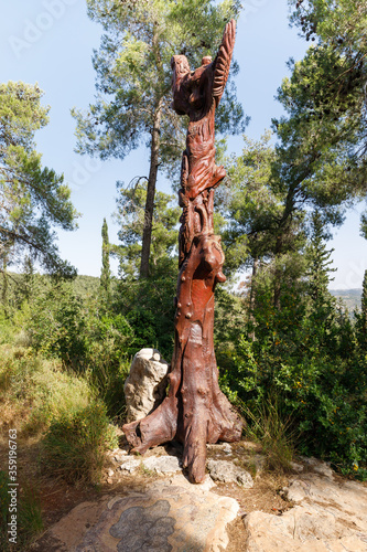 A standing wooden pillar with various figures carved on it in the Totem park in the forest near the villages of Har Adar and Abu Ghosh