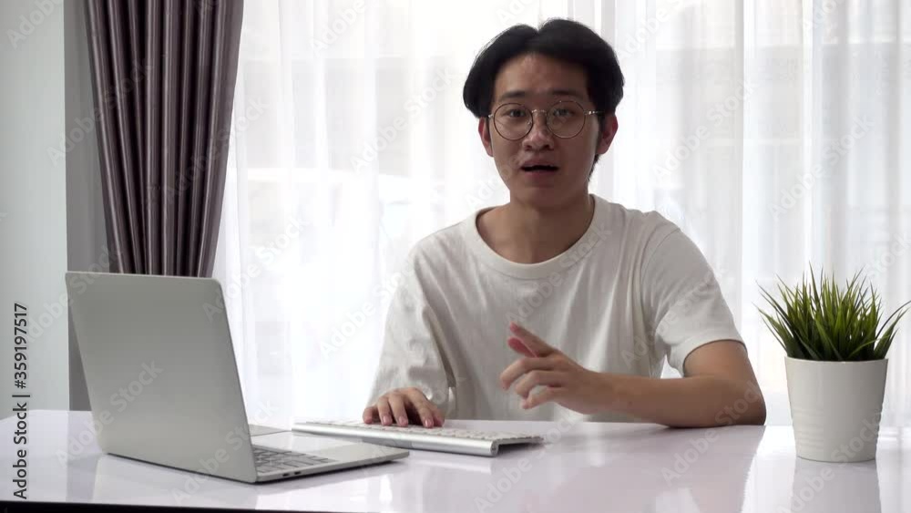 Happy Asian businessman freelancer he work from home during coronavirus disease he is talking explain to her colleagues about plan in video conference online and use his laptop computer Happy Asian businessman freelancer he work from home during coronavirus disease he is talking explain to her colleagues about plan in video conference online and use his laptop computer