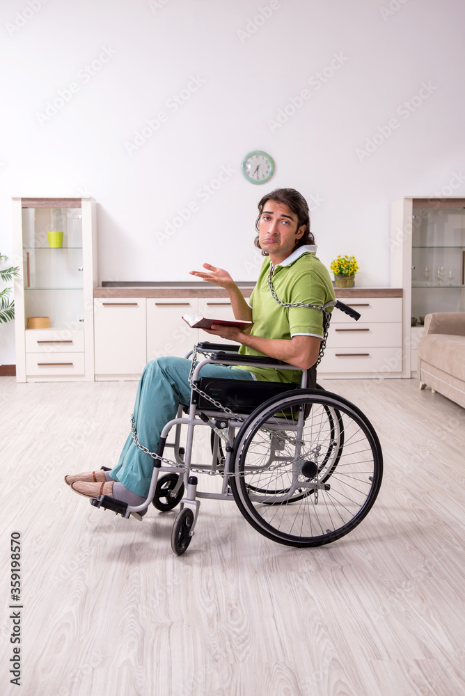 Young male invalid in wheel-chair suffering at home Young male invalid in wheel-chair suffering at home