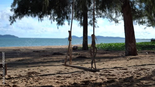 Wooden swing at beach moving in background of the sea 