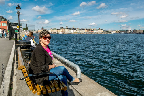  A woman sits on a bench on the embankment in Stockholm. © toshket