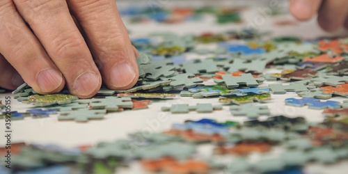 senior man doing colorful puzzles sitting at light table in room close view