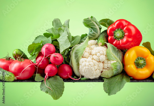 Various fresh raw vegetables on a green background.