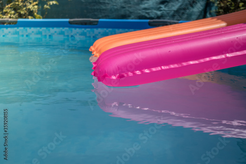 Colchonetas de color rosa y naranja en una piscina desmontable llena de agua photo