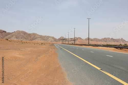 Modern asphalt highway passes through arid desert sand dunes terrain in Sharjah emirate in the United Arab Emirates.   © Arnold Pinto
