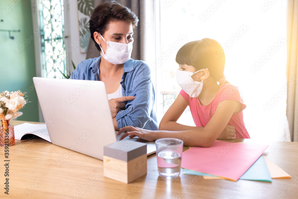mother and daughter wearing surgical mask and working at home mother and daughter wearing surgical mask and working at home