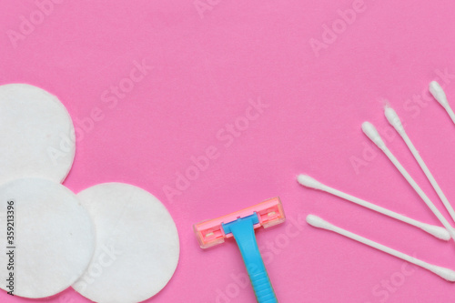 Beauty still life, minimalism. Plastic epilator razor with cotton circles and ear sticks on pink background. Women's accessories for beauty care. Top view. Copy space