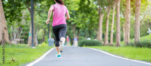 Young adult female in sportswear running in the park outdoor, runner woman jogging on the road, asian Athlete walking and exercise in morning. Fitness, wellness, healthy lifestyle and workout concepts