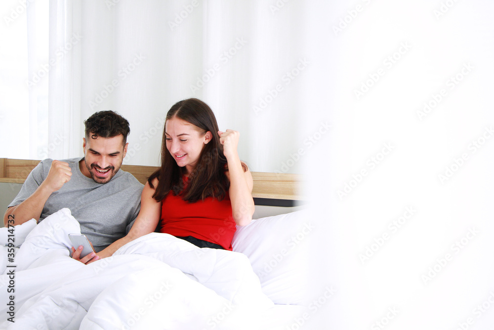 Smiling Caucasian Couple love relaxing and working online for business on laptop in social media technology in bedroom. Work from home and family lifestyle on holiday Concept. Smiling Caucasian Couple love relaxing and working online for business on laptop in social media technology in bedroom. Work from home and family lifestyle on holiday Concept.