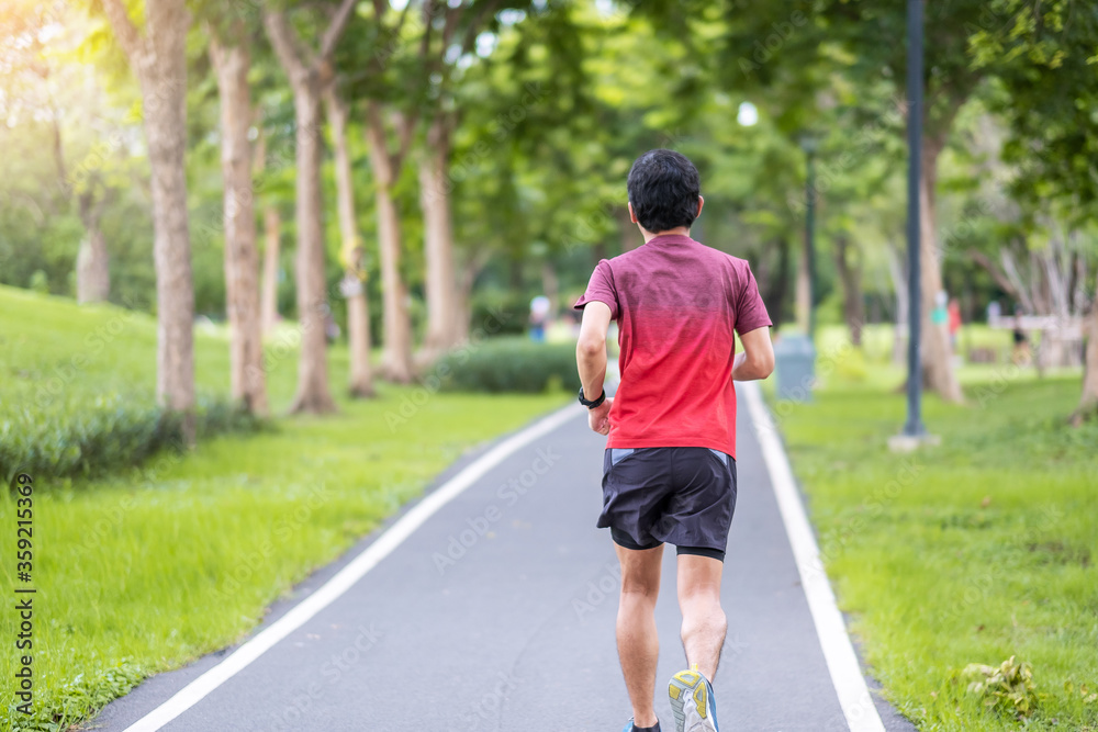 Young adult male in sportswear running in the park outdoor, runner man jogging on the road, asian Athlete walking and exercise in morning. Fitness, wellness, healthy lifestyle and workout concepts