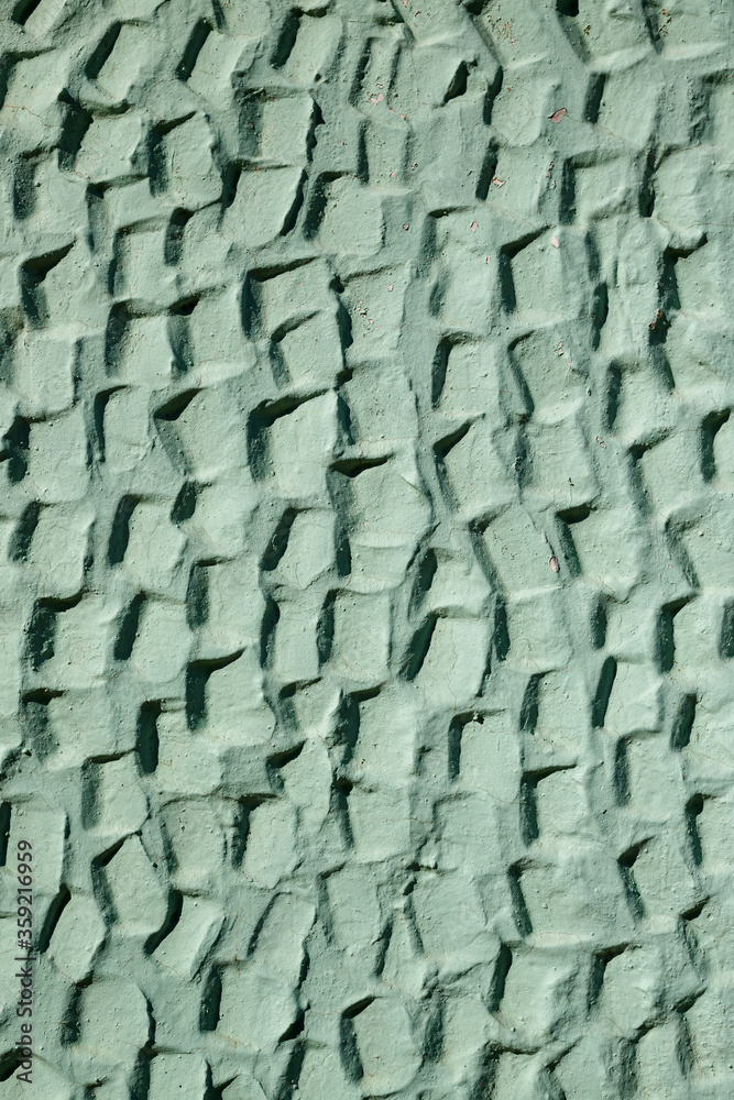 Fototapeta premium The texture of the plastered wall. Rough corrugated cement surface. Faded green color. Uneven angular pattern. Perfect for background and design.