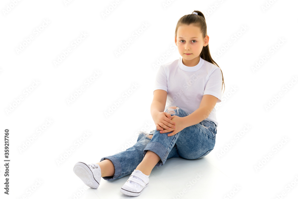 A little girl is sitting on the floor in a clean white T-shirt. A little girl is sitting on the floor in a clean white T-shirt.