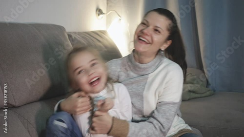 Happy woman laughing and tickle her daughter in home interior