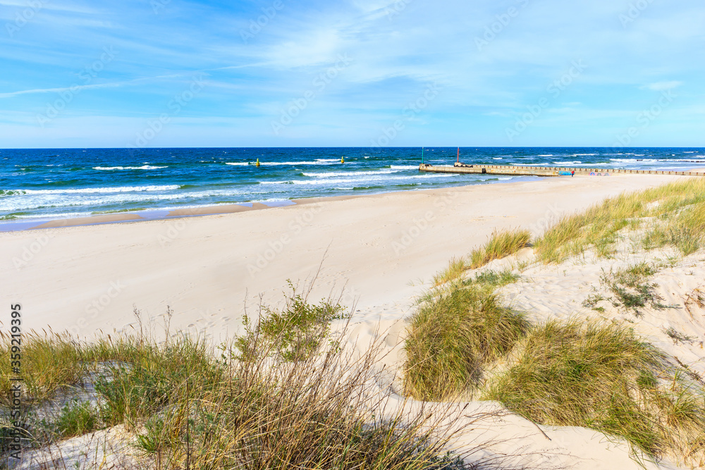 Grass sand dunes and beautiful white sand beach with blue sea near Kolobrzeg, Baltic Sea coast, Poland Grass sand dunes and beautiful white sand beach with blue sea near Kolobrzeg, Baltic Sea coast, Poland